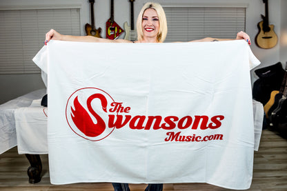 A woman holding a white blanket with the swansons logo on it.