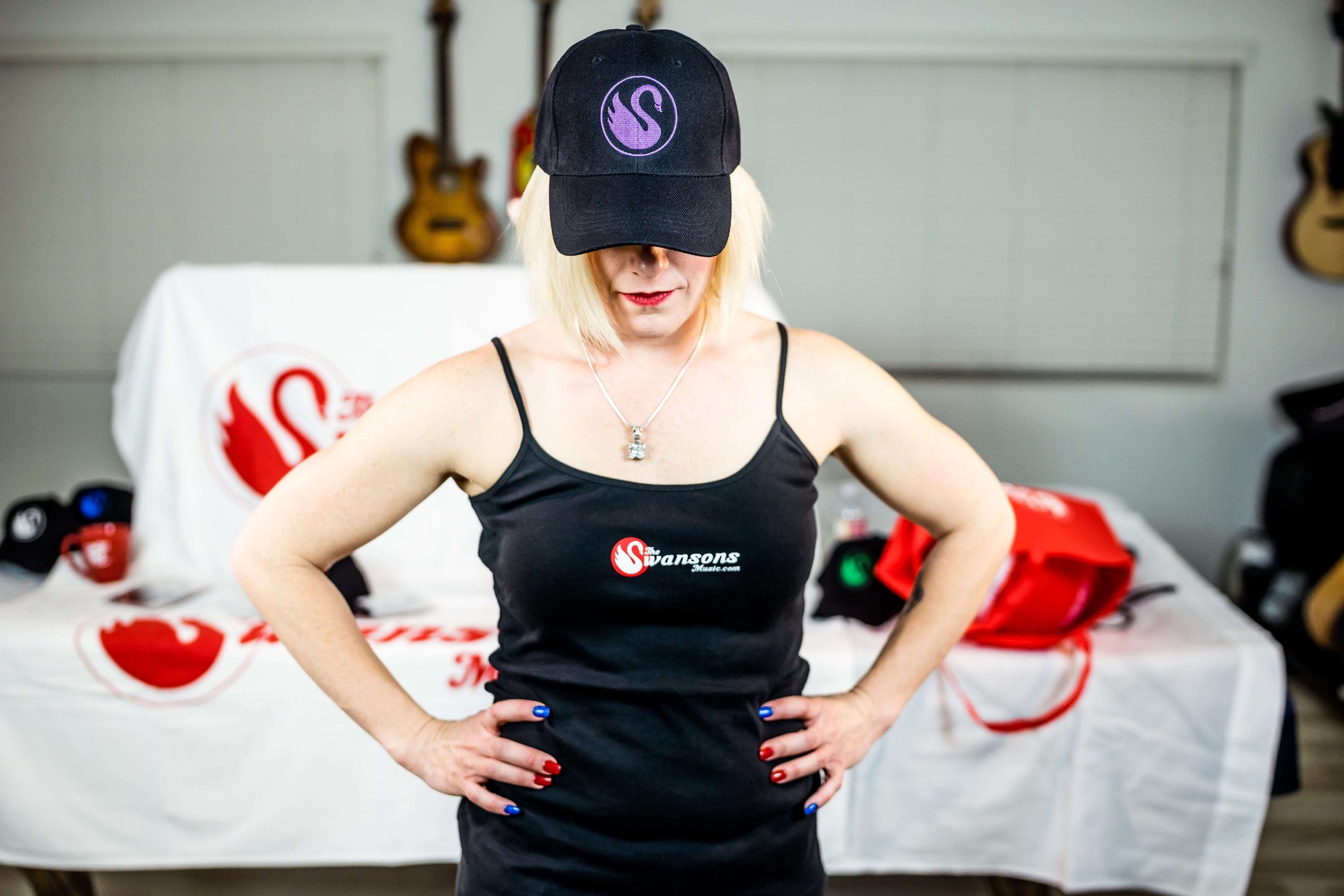 A woman in a black dress and hat standing in front of a table.