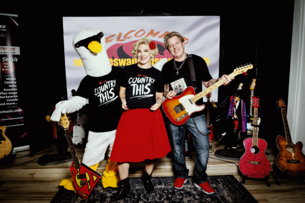 A man and a woman posing with Country This T-shirts adult (unisex) and a mascot.