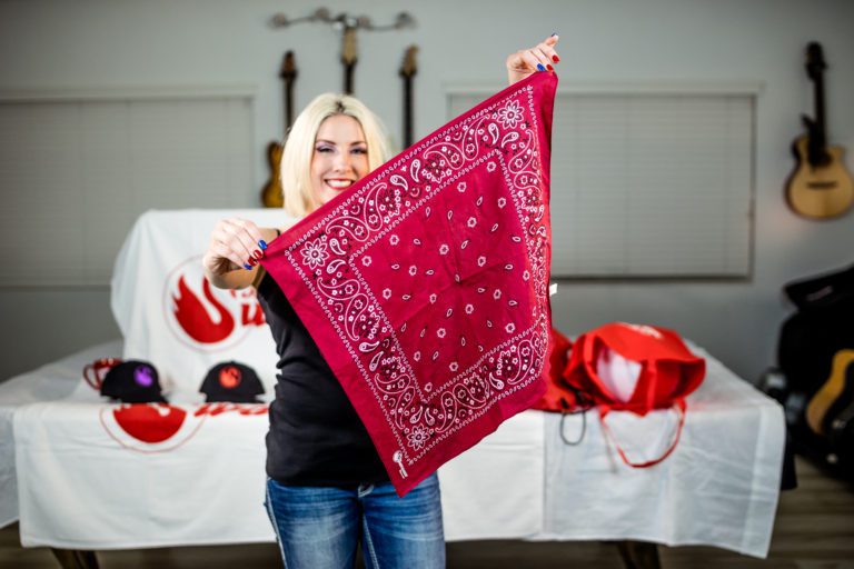 A woman holding up a red bandana.