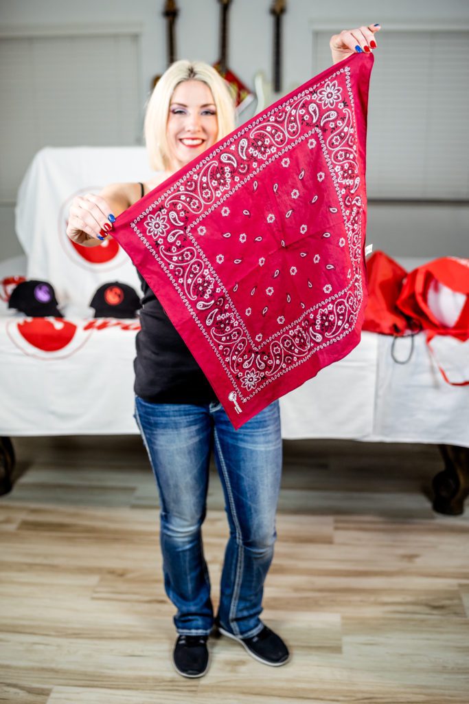 A woman holding up a red bandana.