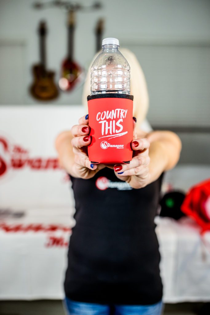 A woman holding up a red can cooler.