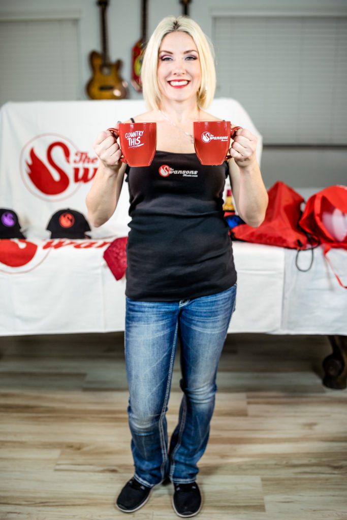 A woman holding up two red mugs.