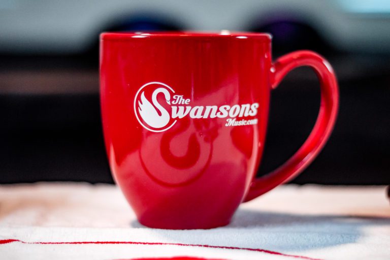 A red coffee mug with the swansons logo on it.