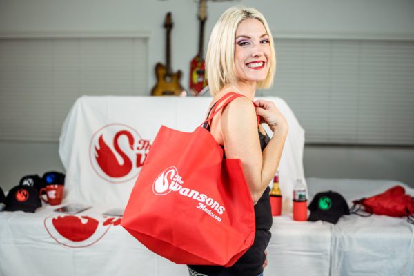 A blonde woman holding a red tote bag.