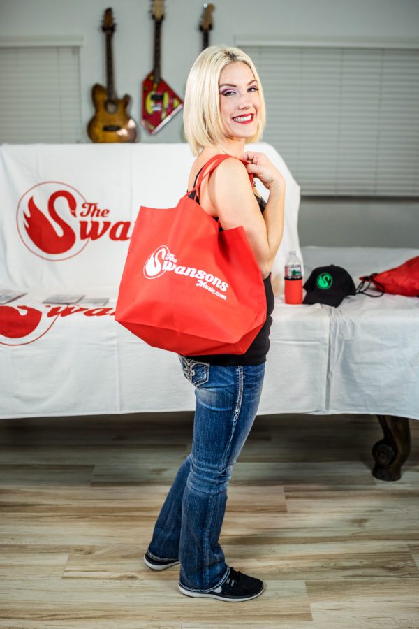 A blonde woman holding a red tote bag.