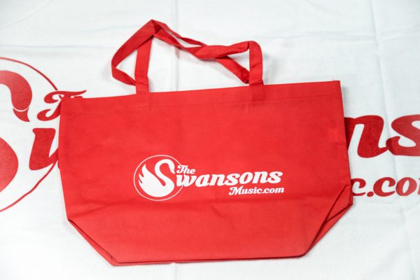 A red tote bag with the swansons logo on it.