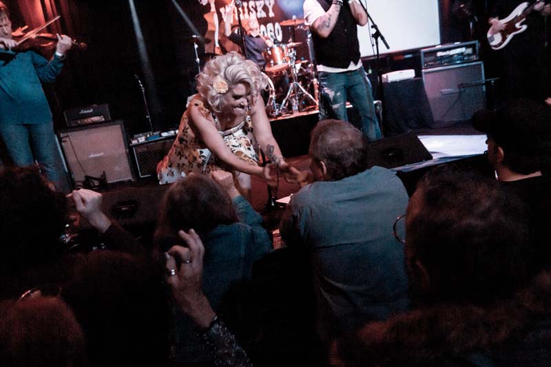 A woman in a dress on stage with a group of people.