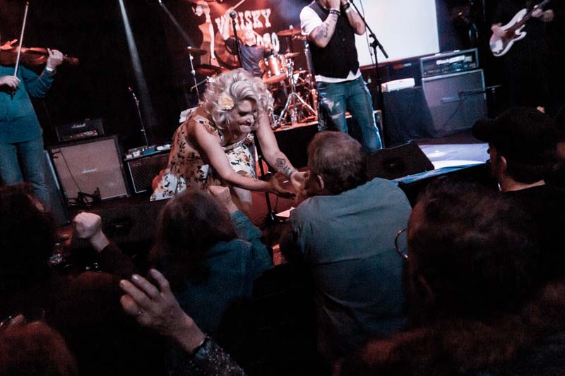 A group of people on stage with a woman holding a microphone.