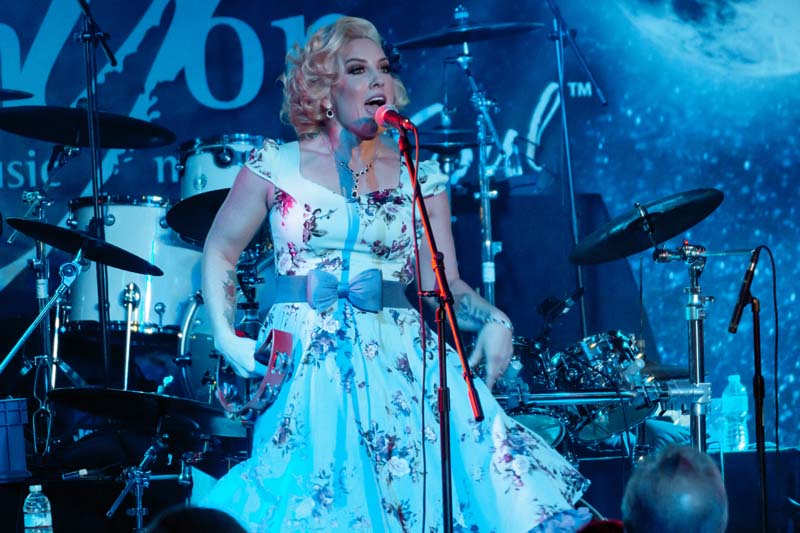 A woman in a dress singing on stage.