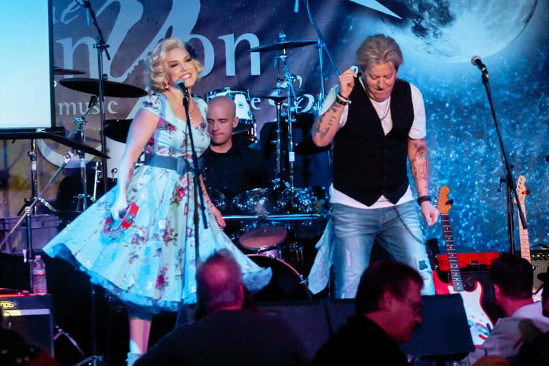 A man and woman singing on stage at an event.