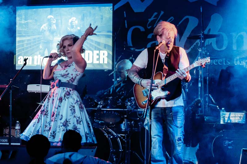 A man and woman singing on stage at a concert.