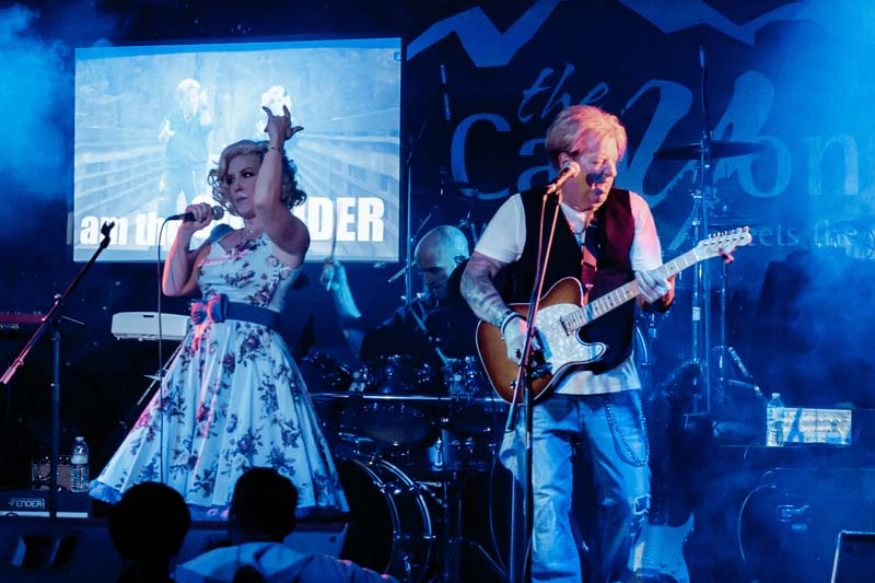 A man and woman playing guitar on stage at a concert.