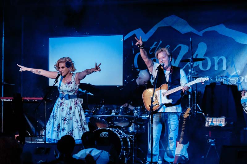 A group of people playing music on stage in front of a mountain.