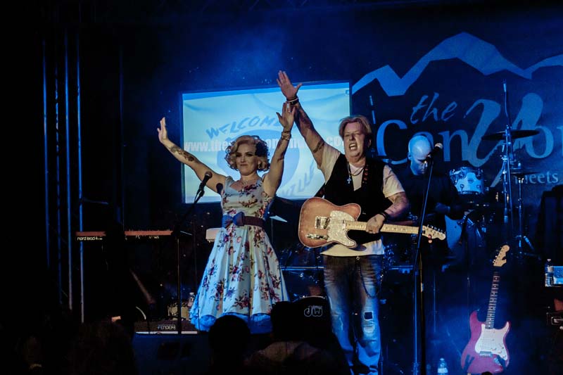 A man and woman singing on stage at a concert.