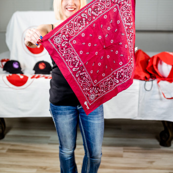 A woman holding up a red bandana.