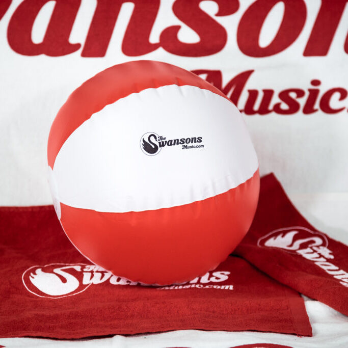 A red and white beach ball with a towel on it.